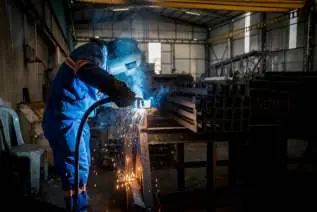 Welder fabricating steel in a workshop