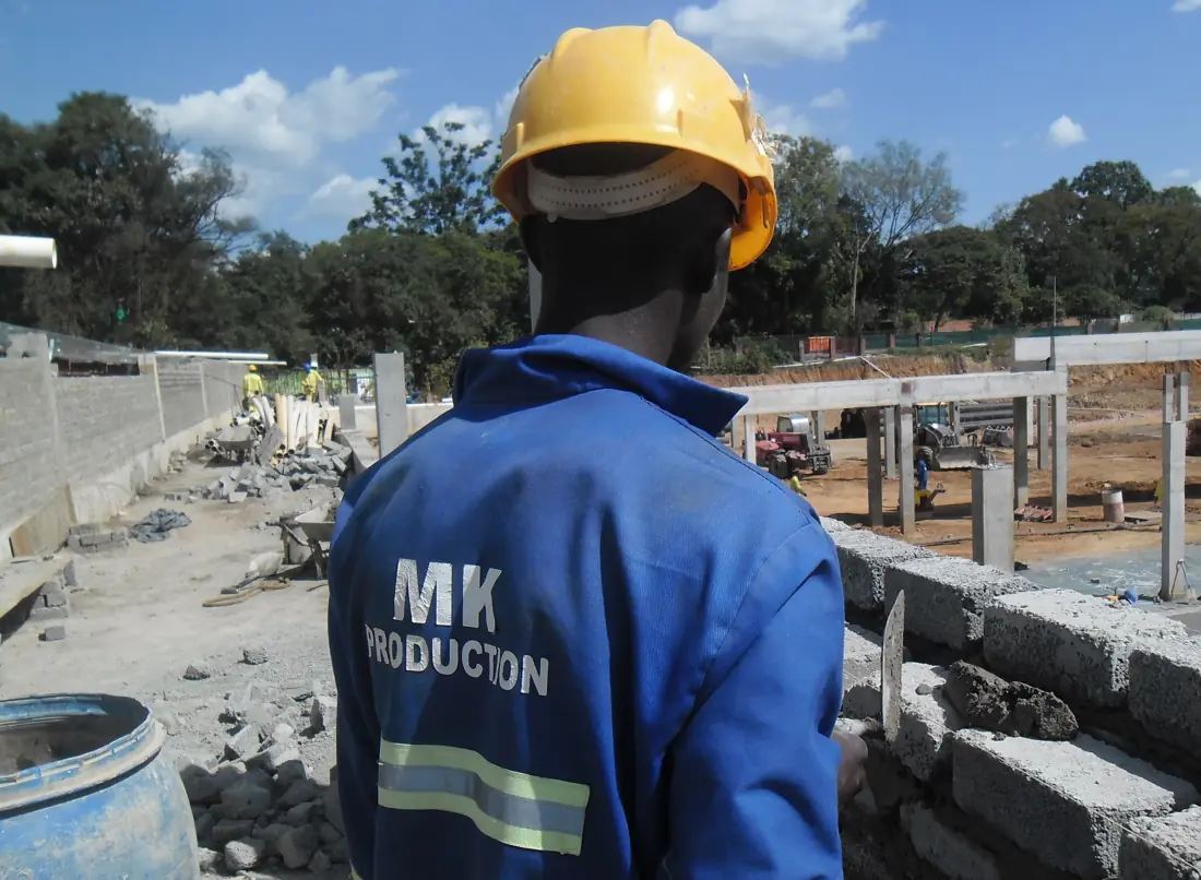 MK Production team member in branded overalls and hard hat on a blockwork site